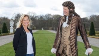 Frau in moderner Kleidung neben einem Mann mit Perücke in Kleidung aus der Barockzeit